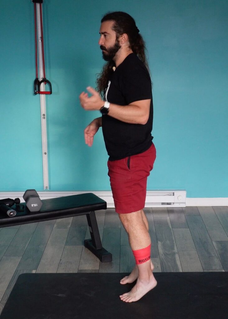 Dr. John doing a calf raise with the muscle floss wrapped around his achilles tendon at the base of his calf muscle